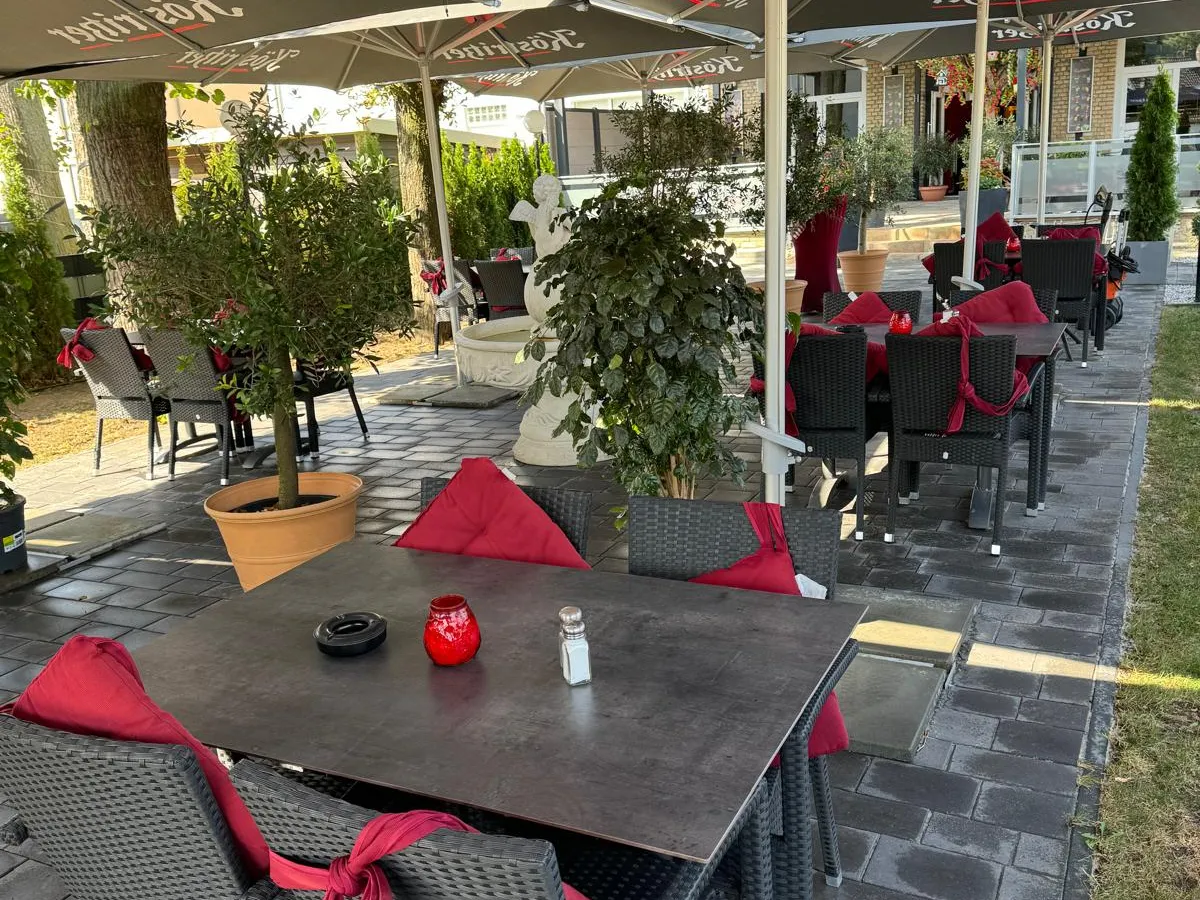 Gedeckter Tisch auf der Terrasse mit roten Kissen